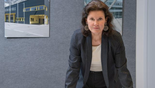 Nicole Rumpler stützt sich auf Tisch auf und schaut in die Kamera
