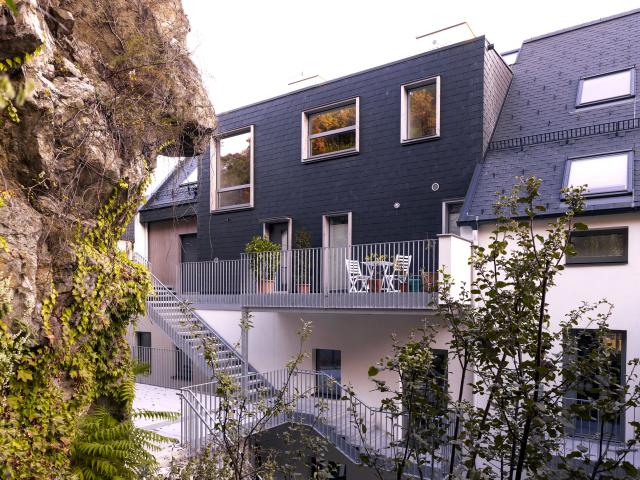Aufgestocktes Winzerhaus an einer Geländekante in Krems mit Felswand und mehrgeschossigem Dachausbau.