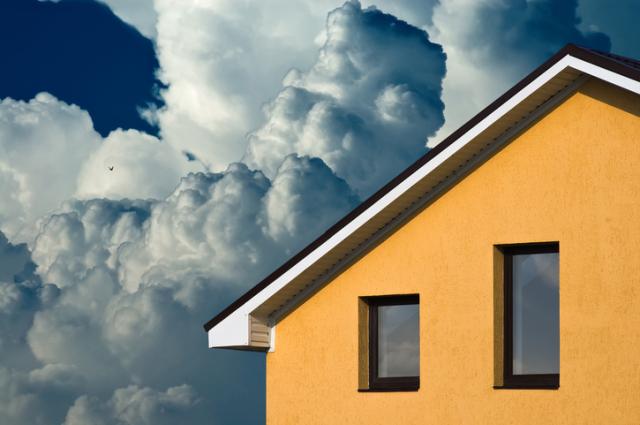 Gelbes Wohnhaus vor großen Gewitterwolken.