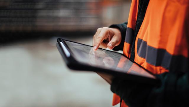 Person mit Tablet und Warnjacke